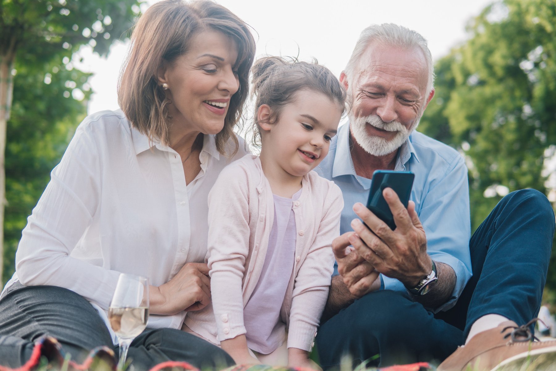 Happy family looking at grandparent's mobile phone